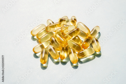 Bunch of omega 3 fish liver oil capsules in pile forming pattern background. Close up of big golden translucent pills texture. Healthy every day nutritional supplement. Top view, flat lay, copy space.