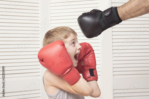 Boy in boxing gloves fights with a man's hand in a glove.