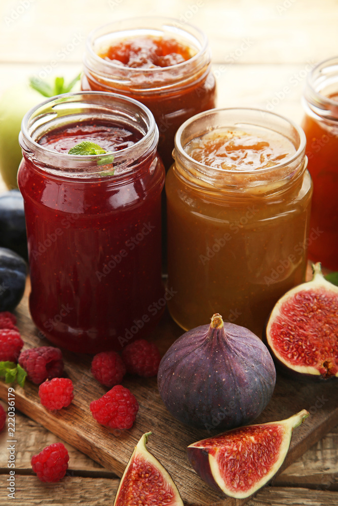 Glass jars with different kinds of jam and berries on wooden table Glass jars with different kinds of jam and berries on wooden table