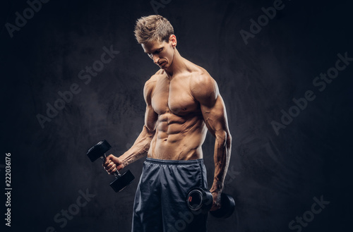 Handsome shirtless man with stylish hair and muscular ectomorph body doing the exercises with dumbbells. photo