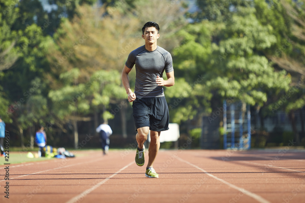 young asian male athlete running on track