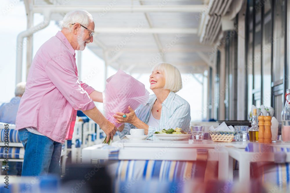 Romantic bouquet. Happy aged woman smiling to her husband while holding a bouquet from him