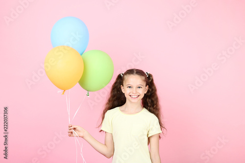 Cute young girl with colored balloons on pink background