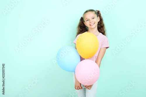 Cute young girl with colored balloons on mint background © 5second
