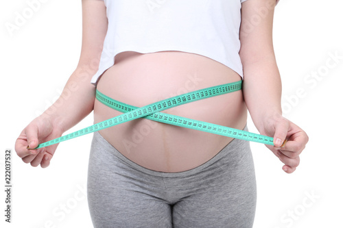 Pregnant woman with measuring tape on white background