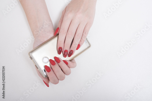 Red manicure with a pattern. Smart phone in female hand. White background