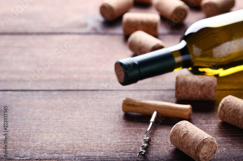 Wine bottle with corks and corkscrew on brown wooden table