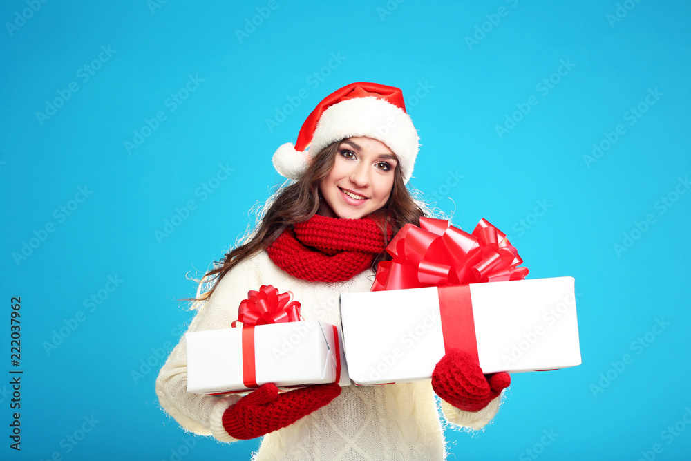 Beautiful young girl holding gift boxes on blue background Beautiful young girl holding gift boxes on blue background