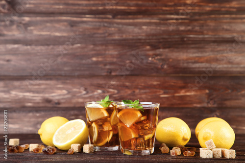 Ice tea in glasses with lemon and mint leafs on wooden table