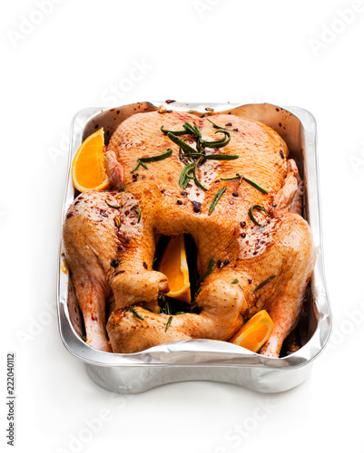 Raw whole duck with spices and oranges in a roasting oventray isolated on white. Ready for cooking. photo