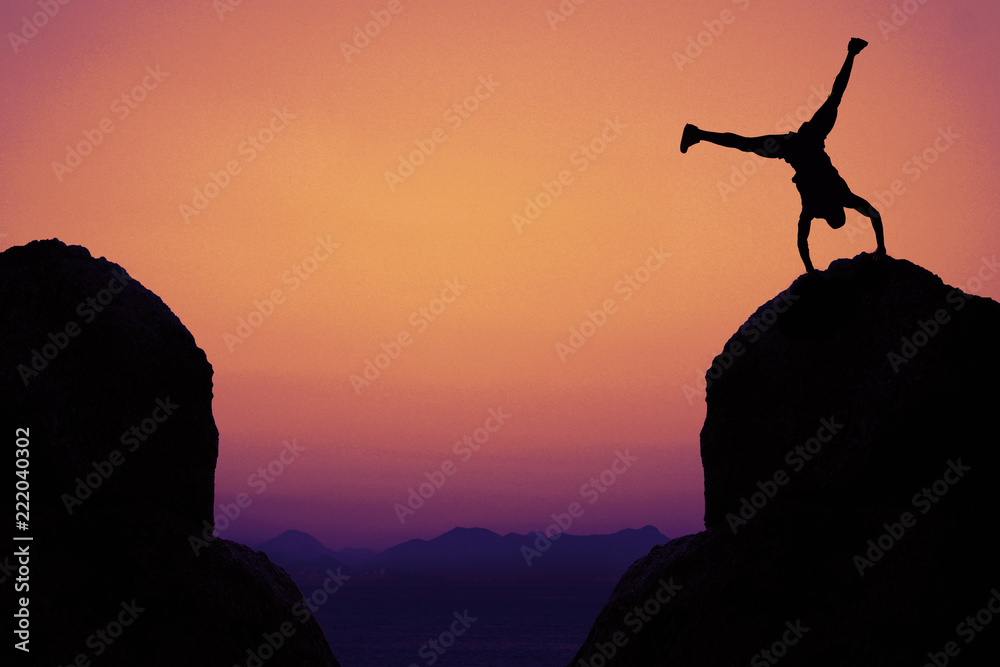 Silhouette of sporty gymnast in mountains as symbol for fun
