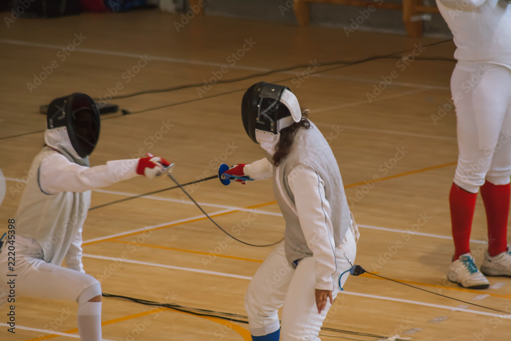 Two teenage fencers competing with foil