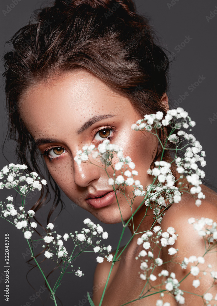 Glamour portrait of beautiful woman model fresh daily makeup, romantic hairstyle.  Fashion highlighter  skin, sexy gloss lips make-up. Cute freckles on young face. Sensual woman with white flowers