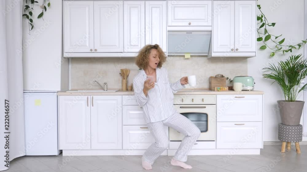 People And Technology Concept. Happy Woman With Smart Phone, Dancing And Smiling In Kitchen