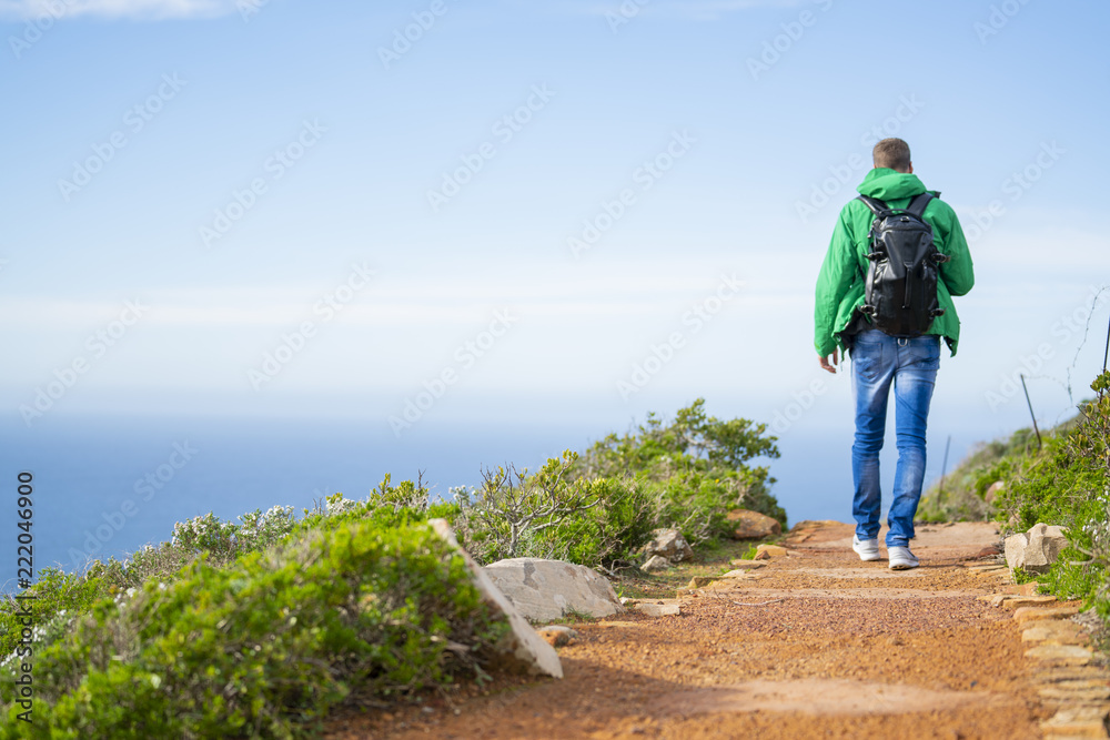 Young man is walking along a beautiful hiking trial at Cape Point, South Africa