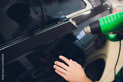 Master installs tint film for car with hairdryer. Concept protection car