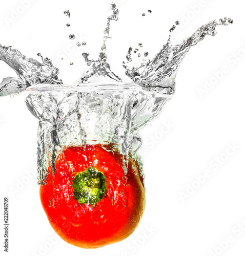 Red bell pepper dropped into liquid creating creative splash