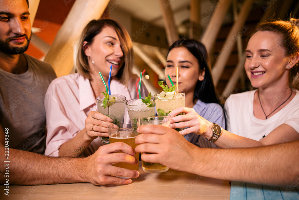 Five cheerful friends sit at the table drinking alcohol Five cheerful friends sit at the table drinking alcohol