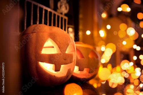 Halloween pumpkins at home on a fireplace with sparkling lights. Cosy autumn background.