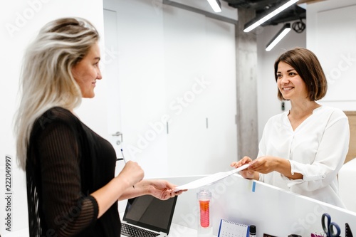 Secretary standing at the reception gives the documents to the employee of the company