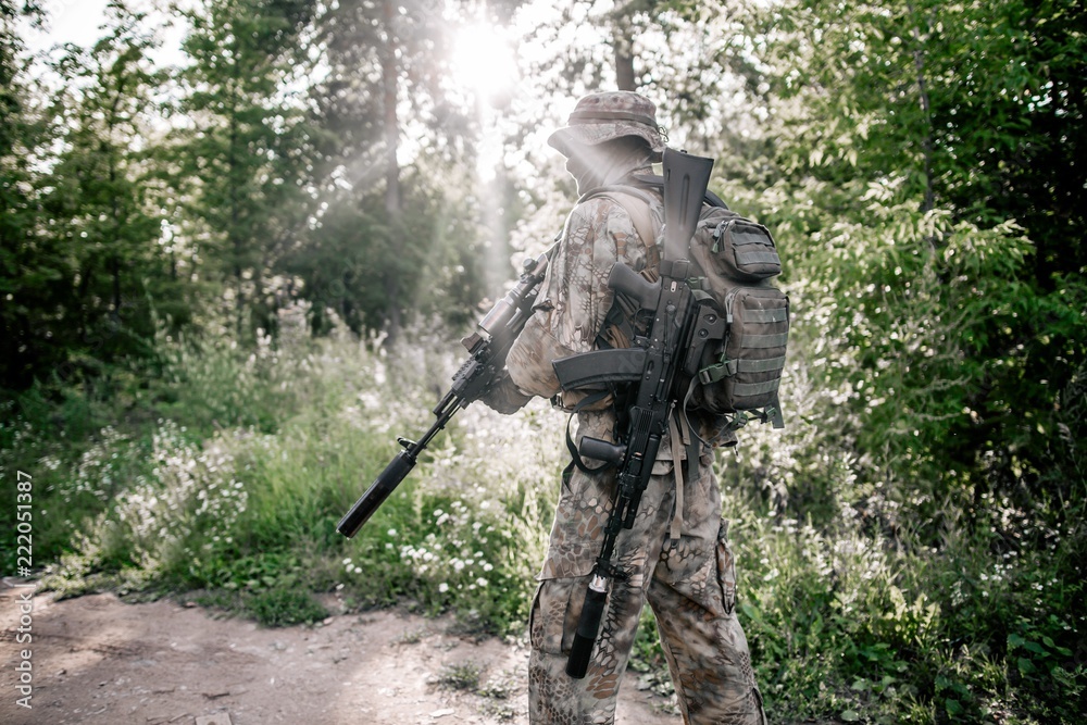 Soldier in camouflage uniform with a rifle in the woods