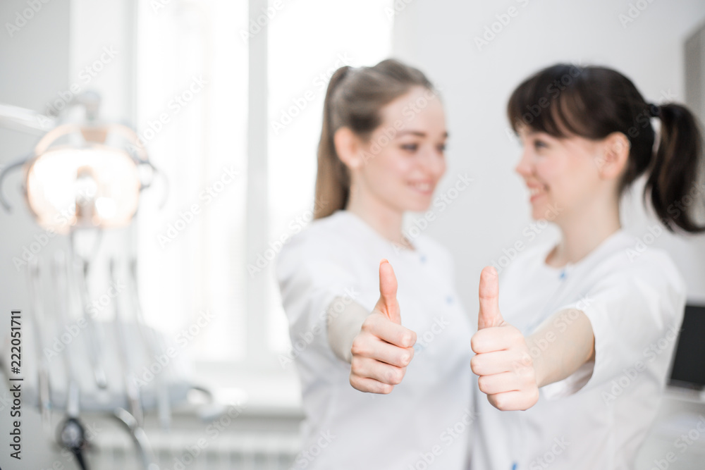 Two dentists show class by lifting their thumbs up in the foreground Two dentists show class by lifting their thumbs up in the foreground