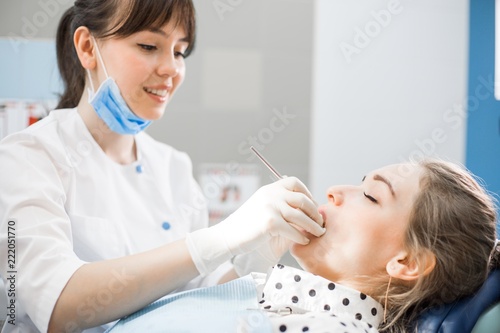 Dentist in white uniform examines the oral cavity of the patient