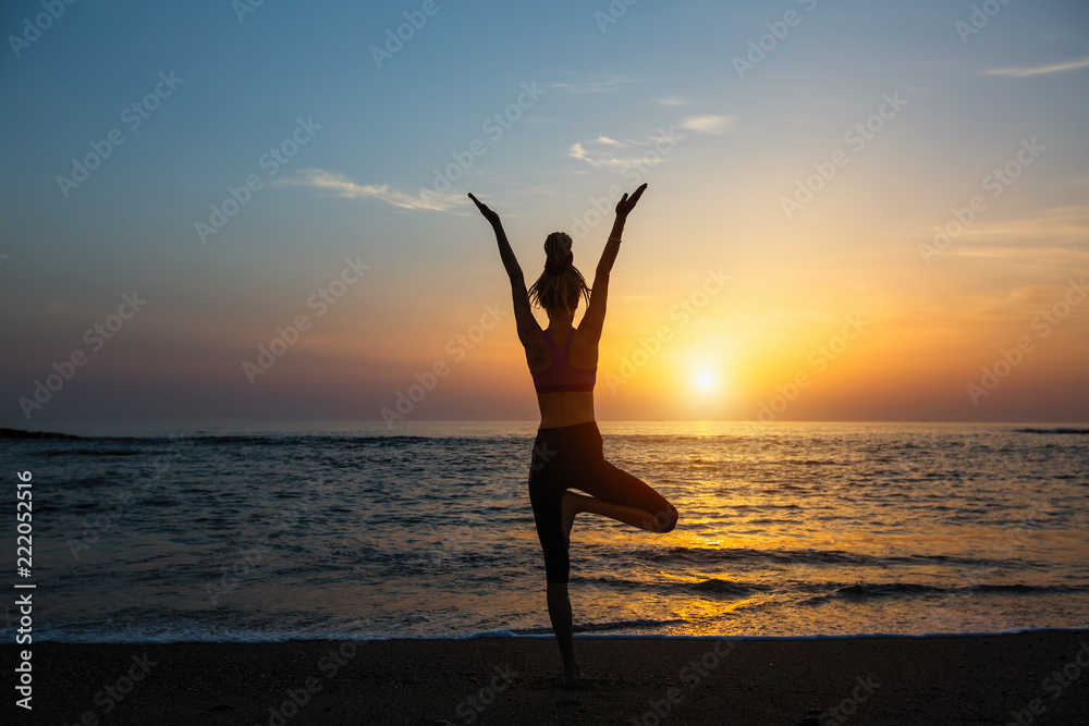 Yoga silhouette meditation fitness woman on the ocean during amazing sunset.