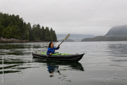 Girl kayaking in the ocean during a cloudy and gloomy sunrise. Taken in Tofino, Vancouver Island, BC, Canada. © edb3_16