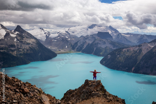 Woman standing on top of the Mountain overlooking a beautiful glacier lake. Taken on Panorama Ridge, Garibaldi, Near Whister, BC, Canada. photo