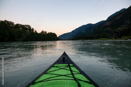 Kayaking in a river surrounded by Canadian Mountains during a vibrant summer sunset. Taken in Squamish, British Columbia, Canada. © edb3_16