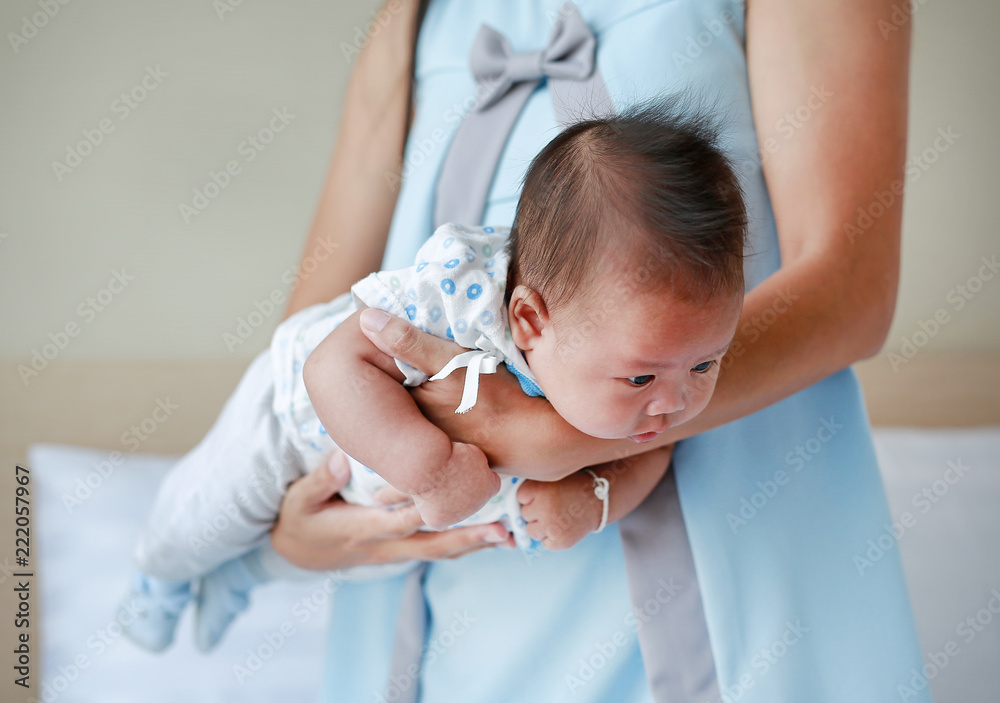 Mother carrying upside down infant baby for decrease baby Stomach pain