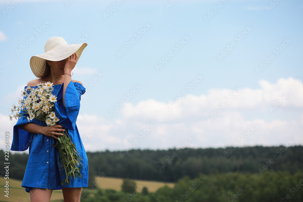Young cute girl in a hat in a field at sunset
