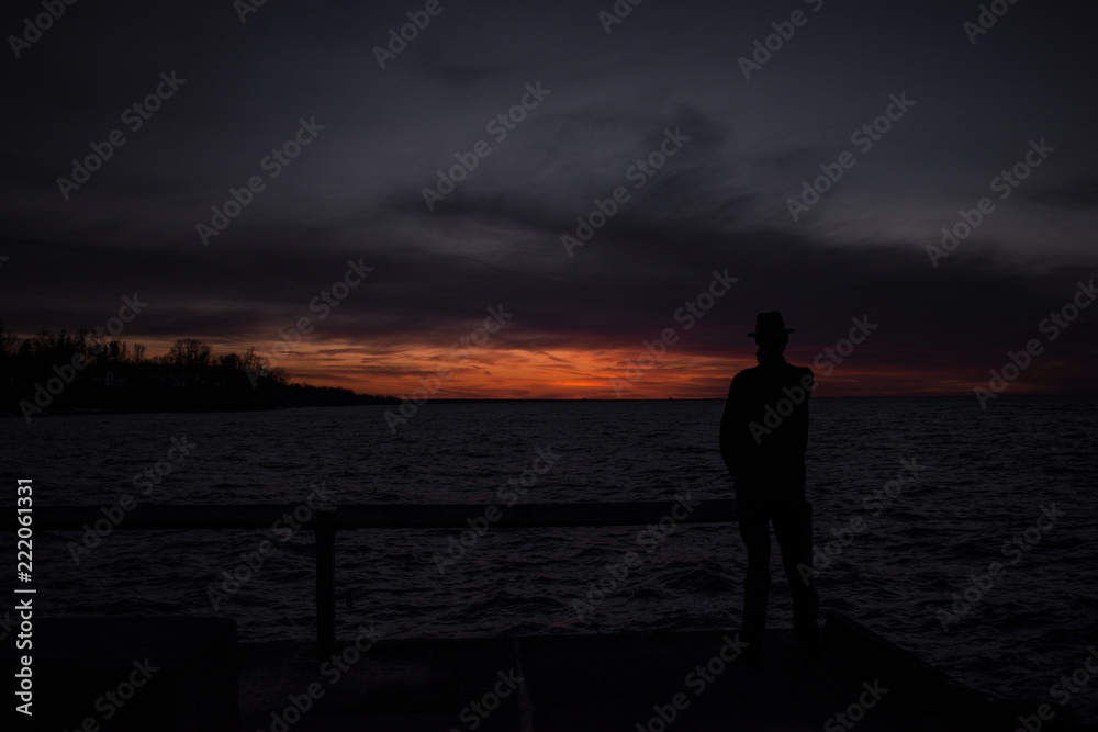 Mysterious silhouette man on the peer at sunset