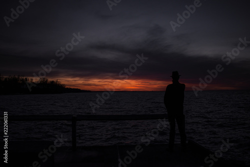 Mysterious silhouette man on the peer at sunset