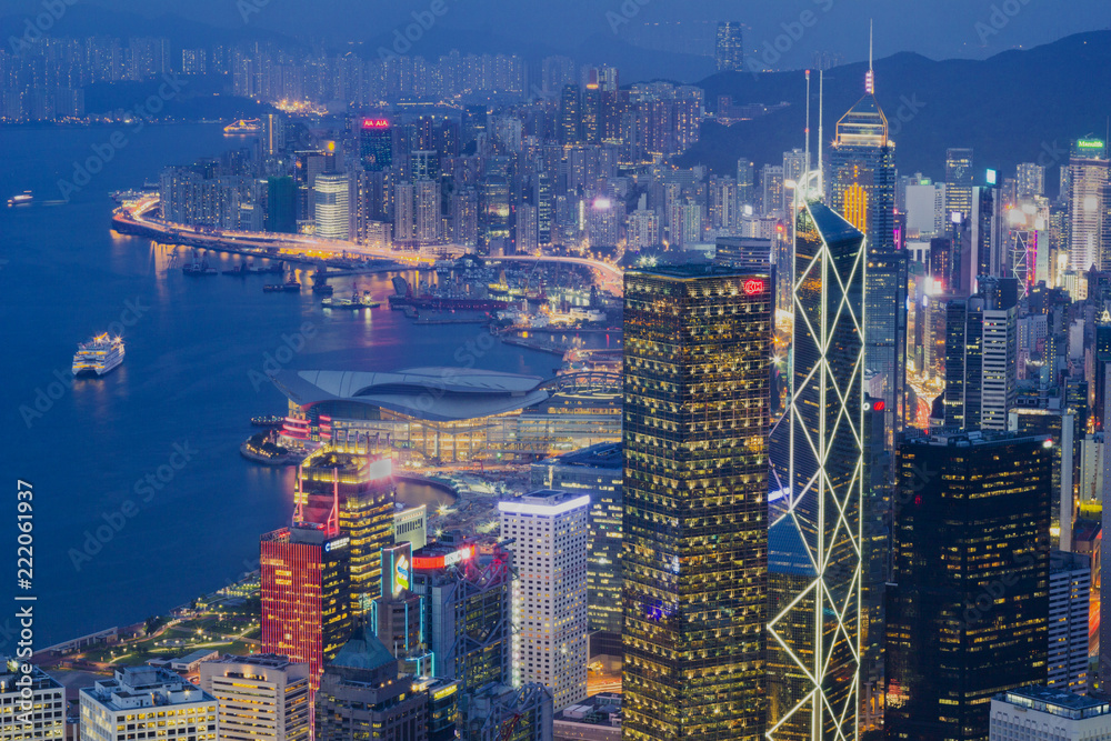 Fototapeta premium Hong Kong city skyline at night. Illuminated skyscrapers on Victoria Harbour with a blue sky.