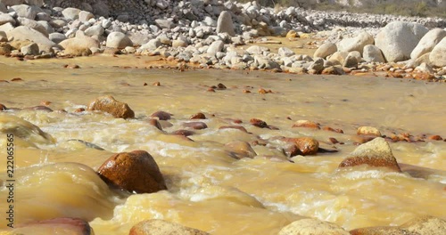 Yellow River, Chilecito. Detail of water flowing along rocky basin. Camera stays still. Rocks at background.La Rioja, Argentina. photo