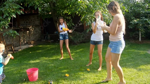 4k footage of happy active family playing with waater guns on grass at backyard photo