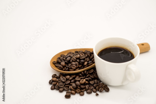 A cup of coffee with small white ceramic dish full of coffee beans