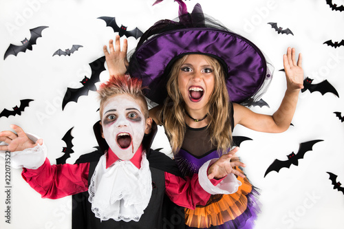 Halloween kids: little girl and boy dressed up in Halloween costumes of witch and vampire Dracula for pumpkin patch and Halloween party