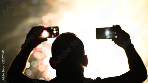 Man films colorful fireworks on two cell phones.