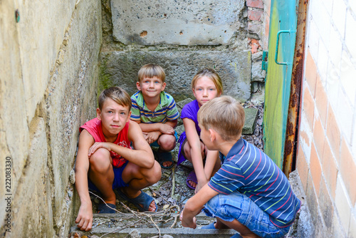 Children in the basement, three boys and a girl near the iron door are hiding on the steps from the outside world. Post-production photo.