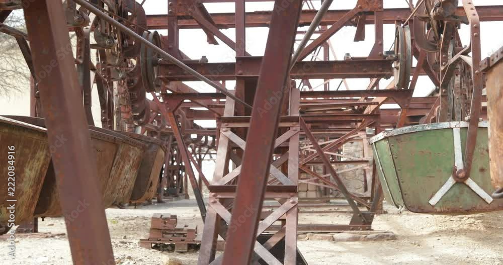 Second station of old Cable Car Chilecito-La Mejicana mine. Rusty iron wagons hanging from rail in linear disposition. Camera moving sideways showing the aligned metal wagons. La Rioja Second station of old Cable Car Chilecito-La Mejicana mine. Rusty iron wagons hanging from rail in linear disposition. Camera moving sideways showing the aligned metal wagons. La Rioja