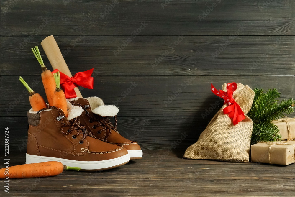 Obraz premium Dutch Holiday Sinterklaas background.Shoen Zetten. Zack van Sinterklaas. Children's shoes, carrots, gifts on brown wooden background. Copy space.