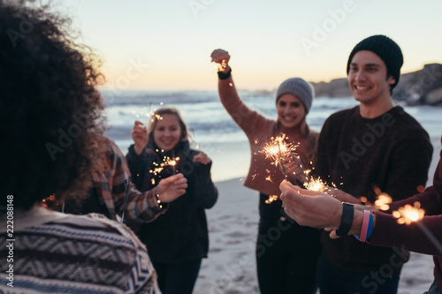 Young people having fun with sparklers at beach