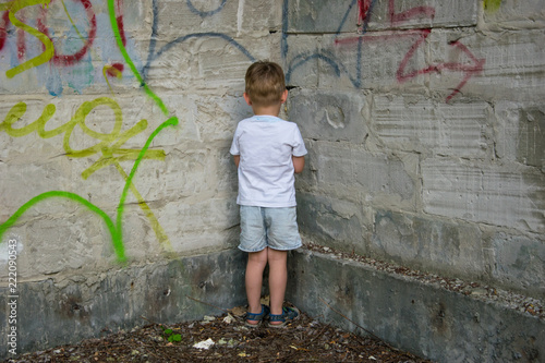 A little boy is standing in the corner as a punishment.