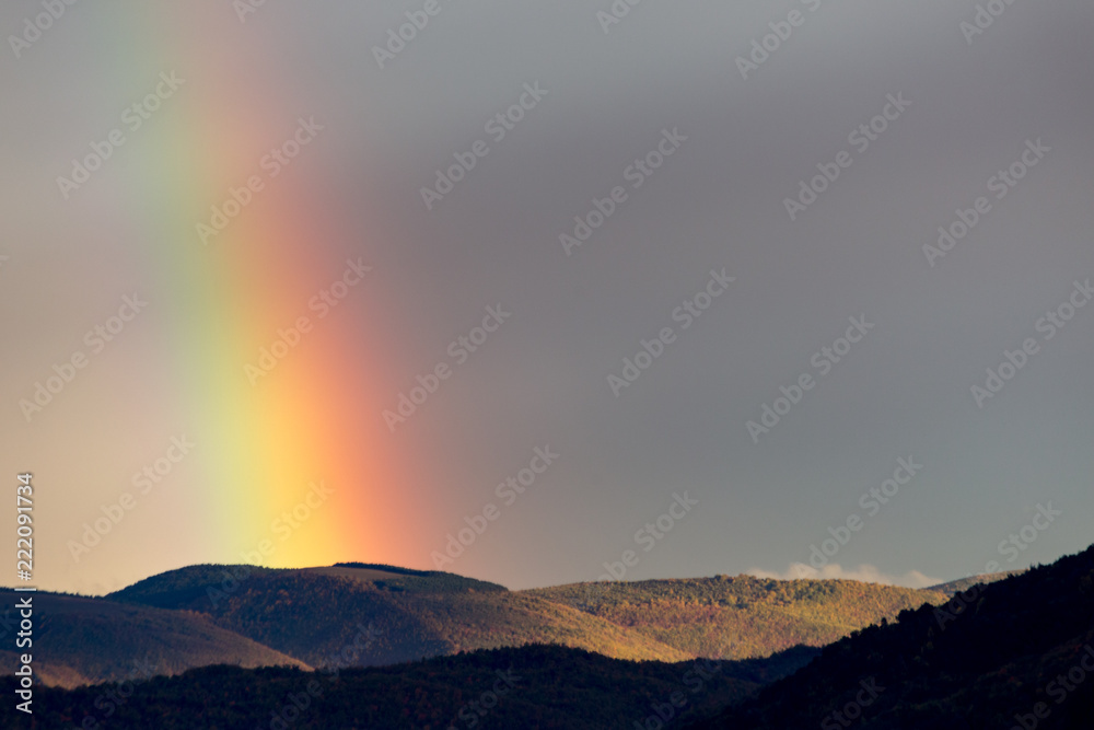 Beautiful and surreal view of part of a rainbow over some hills