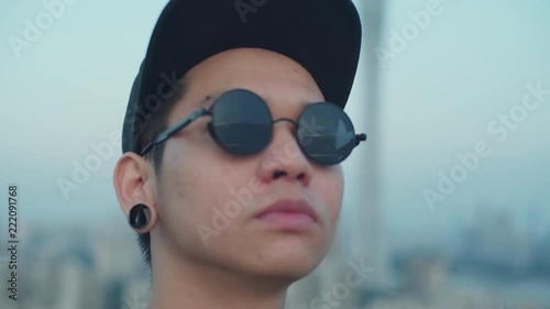 Close up on a young asian photographer capturing skyline reflected in his sunglasses from the rooftop in the early morning photo