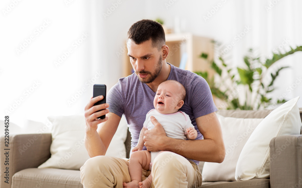 family, parenthood and technology concept - father with crying little baby and smartphone at home family, parenthood and technology concept - father with crying little baby and smartphone at home