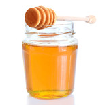 Flüssig gelbe Honig in glass mit holzenem Löffel. Eine Isolierung auf weiss.